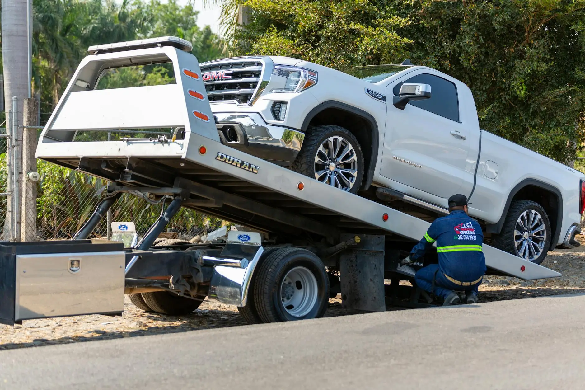 A clean, modern flatbed tow truck parked safely along Brookpark Road in Brooklyn, OH.